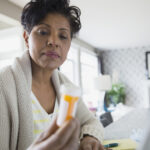 Woman reading prescription bottle label.