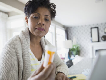 Woman reading prescription bottle label.