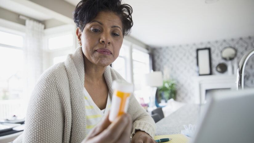 Woman reading prescription bottle label.