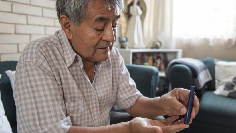close up, older adult draws blood from a finger to check his blood sugar levels. health care concept from home