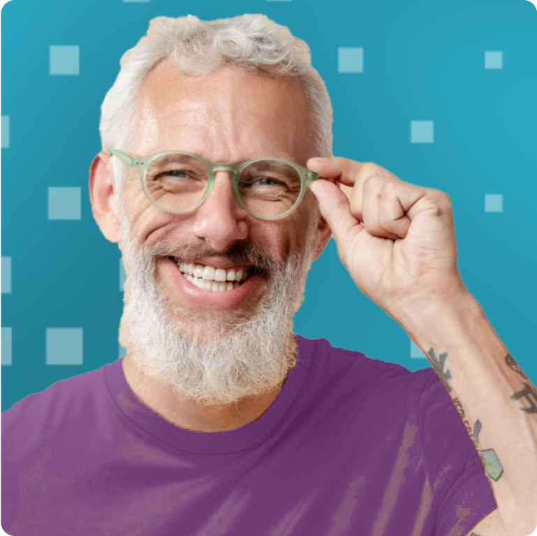 A joyful man with a white beard and green glasses, adjusting his frames while smiling, with a vibrant teal background. Ideal for content on modern seniors and style.